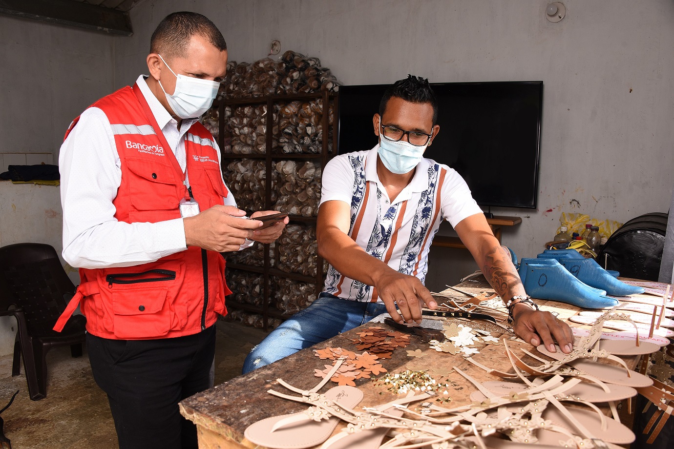 El emprendedor colombiano Leonar Palencia, en su zapatería durante la visita del asesor de Bancamía (FMBBVA) usando una tableta